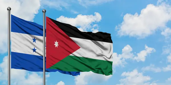 Bandera de Honduras y Jordania ondeando en el viento contra el cielo azul nublado blanco juntos. Concepto diplomático, relaciones internacionales . — Foto de Stock
