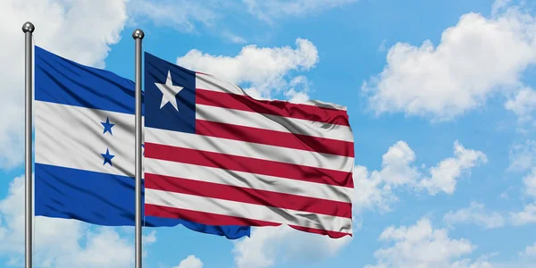 Honduras i Liberia flaga machając w wiatr przed białym zachmurzone błękitne niebo razem. Koncepcja dyplomacji, stosunki międzynarodowe. — Zdjęcie stockowe