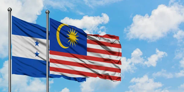 Honduras and Malaysia flag waving in the wind against white cloudy blue sky together. Diplomacy concept, international relations. — Stock Photo, Image