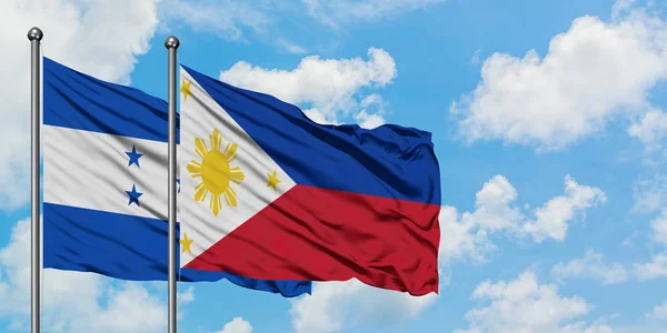 Bandera de Honduras y Filipinas ondeando en el viento contra el cielo azul nublado blanco juntos. Concepto diplomático, relaciones internacionales . — Foto de Stock