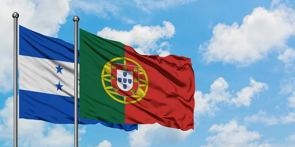 Bandera de Honduras y Portugal ondeando en el viento contra el cielo azul nublado blanco juntos. Concepto diplomático, relaciones internacionales . — Foto de Stock