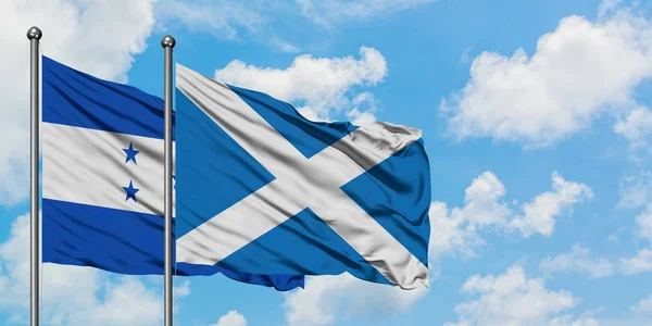 Ονδούρα και Σκωτία σημαία που κουνώντας τον άνεμο κατά λευκό συννεφιασμένο γαλάζιο του ουρανού μαζί. Φιλοσοφία της διπλωματίας, διεθνείς σχέσεις. — Φωτογραφία Αρχείου