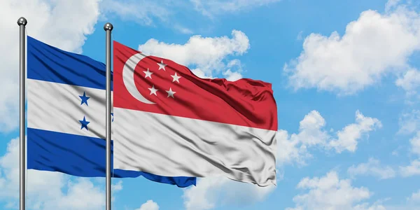 Гондурас и Сингапур вместе размахивают на ветру белым облачно-голубым небом. Концепция дипломатии, международные отношения . — стоковое фото