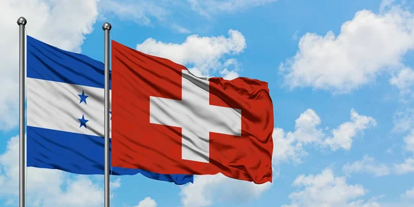 Honduras i Szwajcaria flaga machając w wiatr przed białym zachmurzone błękitne niebo razem. Koncepcja dyplomacji, stosunki międzynarodowe. — Zdjęcie stockowe