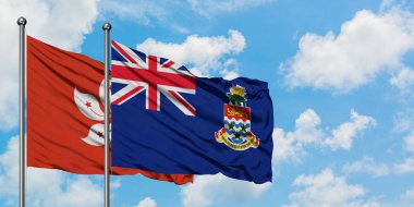 Hong Kong ve Cayman Adaları bayrağı birlikte beyaz bulutlu mavi gökyüzüne karşı rüzgarda sallayarak. Diplomasi kavramı, uluslararası ilişkiler.
