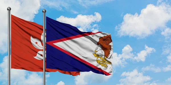 Bandera de Hong Kong y Samoa Americana ondeando en el viento contra el cielo azul nublado blanco juntos. Concepto diplomático, relaciones internacionales . —  Fotos de Stock