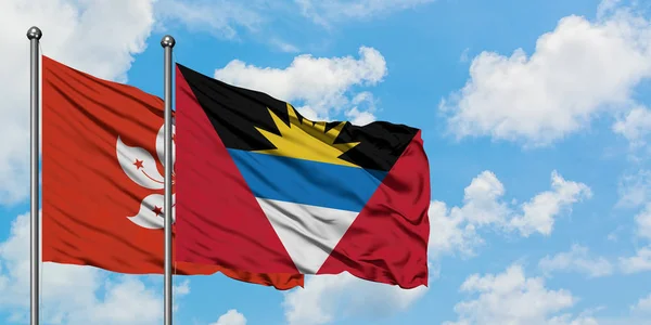Hong Kong ve Antigua ve Barbuda bayrağı birlikte beyaz bulutlu mavi gökyüzüne karşı rüzgarda sallayarak. Diplomasi kavramı, uluslararası ilişkiler. — Stok fotoğraf