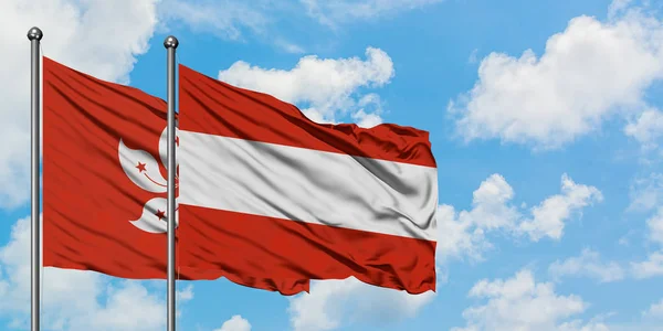 Bandeira de Hong Kong e Áustria agitando no vento contra o céu azul nublado branco juntos. Conceito de diplomacia, relações internacionais . — Fotografia de Stock