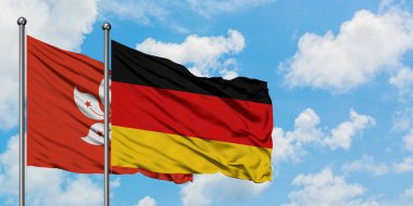 Hong Kong ve Almanya bayrağı birlikte beyaz bulutlu mavi gökyüzüne karşı rüzgarda sallayarak. Diplomasi kavramı, uluslararası ilişkiler.