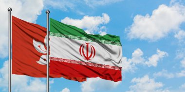 Hong Kong ve İran bayrağı birlikte beyaz bulutlu mavi gökyüzüne karşı rüzgarda sallayarak. Diplomasi kavramı, uluslararası ilişkiler.