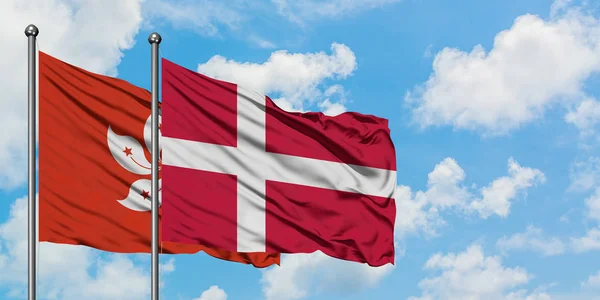 Drapeau de Hong Kong et du Danemark agitant dans le vent contre ciel bleu nuageux blanc ensemble. Concept de diplomatie, relations internationales . — Photo