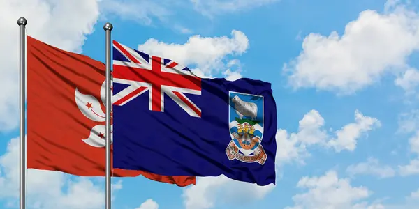 Bandera de Hong Kong e Islas Malvinas ondeando en el viento contra el cielo azul nublado blanco juntos. Concepto diplomático, relaciones internacionales . — Foto de Stock