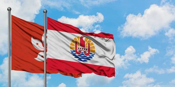 Bandera de Hong Kong y Polinesia Francesa ondeando en el viento contra el cielo azul nublado blanco juntos. Concepto diplomático, relaciones internacionales . — Foto de Stock