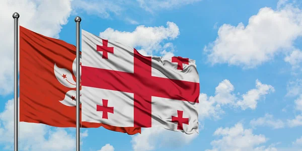 Hong Kong and Georgia flag waving in the wind against white cloudy blue sky together. Diplomacy concept, international relations. — Stock Photo, Image