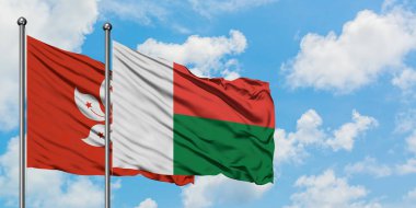 Hong Kong ve Madagaskar bayrağı birlikte beyaz bulutlu mavi gökyüzüne karşı rüzgarda sallayarak. Diplomasi kavramı, uluslararası ilişkiler.