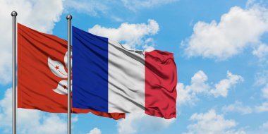 Hong Kong ve Reunion bayrağı birlikte beyaz bulutlu mavi gökyüzüne karşı rüzgarda sallayarak. Diplomasi kavramı, uluslararası ilişkiler.