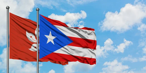 Hong Kong ve Porto Riko bayrağı birlikte beyaz bulutlu mavi gökyüzüne karşı rüzgarda sallayarak. Diplomasi kavramı, uluslararası ilişkiler. — Stok fotoğraf