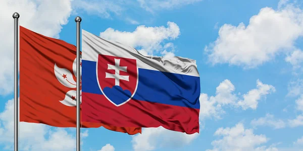 Hongkong och Slovakien flagga vifta i vinden mot vit grumlig blå himmel tillsammans. Diplomatisk koncept, internationella relationer. — Stockfoto