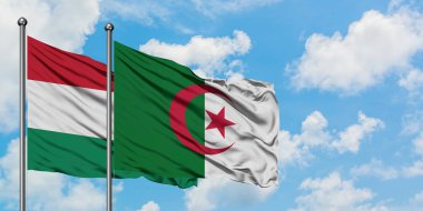 Macaristan ve Cezayir bayrağı birlikte beyaz bulutlu mavi gökyüzüne karşı rüzgarda sallayarak. Diplomasi kavramı, uluslararası ilişkiler.