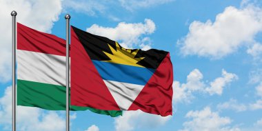 Macaristan ve Antigua ve Barbuda bayrağı birlikte beyaz bulutlu mavi gökyüzüne karşı rüzgarda sallayarak. Diplomasi kavramı, uluslararası ilişkiler.