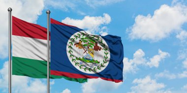 Macaristan ve Belize bayrağı birlikte beyaz bulutlu mavi gökyüzüne karşı rüzgarda sallayarak. Diplomasi kavramı, uluslararası ilişkiler.