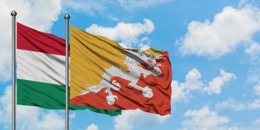 Macaristan ve Bhutan bayrağı birlikte beyaz bulutlu mavi gökyüzüne karşı rüzgarda sallayarak. Diplomasi kavramı, uluslararası ilişkiler.