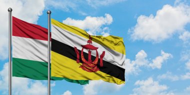 Macaristan ve Brunei bayrağı birlikte beyaz bulutlu mavi gökyüzüne karşı rüzgarda sallayarak. Diplomasi kavramı, uluslararası ilişkiler.