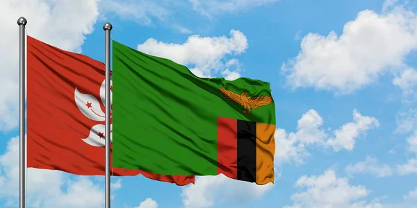 Hong Kong and Zambia flag waving in the wind against white cloudy blue sky together. Diplomacy concept, international relations. — Stock Photo, Image