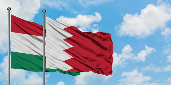 Bandera de Hungría y Bahréin ondeando en el viento contra el cielo azul nublado blanco juntos. Concepto diplomático, relaciones internacionales . — Foto de Stock