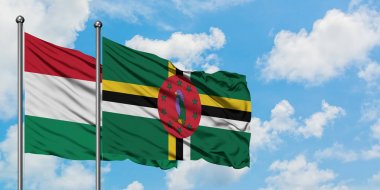 Macaristan ve Dominika bayrağı birlikte beyaz bulutlu mavi gökyüzüne karşı rüzgarda sallayarak. Diplomasi kavramı, uluslararası ilişkiler.