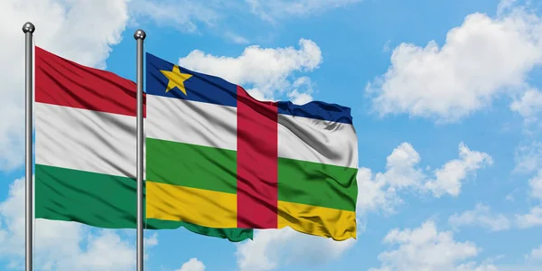 Bandera de Hungría y República Centroafricana ondeando en el viento contra el cielo azul nublado blanco juntos. Concepto diplomático, relaciones internacionales . — Foto de Stock