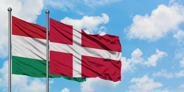 Maďarsko a Dánská vlajka mávali ve větru proti bíle zatažené modré obloze. Diplomacie, mezinárodní vztahy. — Stock fotografie