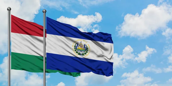 Macaristan ve El Salvador bayrağı birlikte beyaz bulutlu mavi gökyüzüne karşı rüzgarda sallayarak. Diplomasi kavramı, uluslararası ilişkiler. — Stok fotoğraf