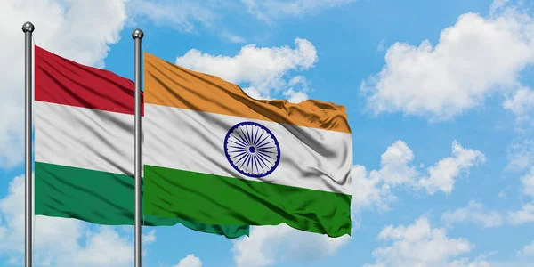 Bandera de Hungría e India ondeando en el viento contra el cielo azul nublado blanco juntos. Concepto diplomático, relaciones internacionales . — Foto de Stock