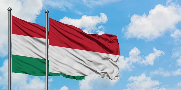 Magyarország és Indonézia zászló integetett a szél elleni fehér felhős kék eget együtt. Diplomáciai koncepció, nemzetközi kapcsolatok. — Stock Fotó