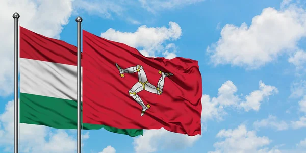 Bandera de Hungría e Isla de Man ondeando en el viento contra el cielo azul nublado blanco juntos. Concepto diplomático, relaciones internacionales . — Foto de Stock
