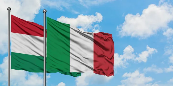 Bandera de Hungría e Italia ondeando en el viento contra el cielo azul nublado blanco juntos. Concepto diplomático, relaciones internacionales . — Foto de Stock