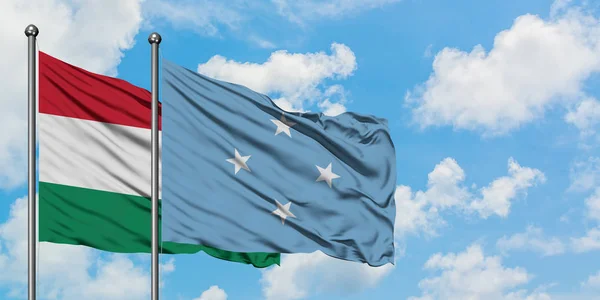 Bandera de Hungría y Micronesia ondeando en el viento contra el cielo azul nublado blanco juntos. Concepto diplomático, relaciones internacionales . — Foto de Stock