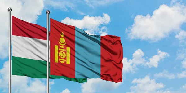 Bandera de Hungría y Mongolia ondeando en el viento contra el cielo azul nublado blanco juntos. Concepto diplomático, relaciones internacionales . — Foto de Stock