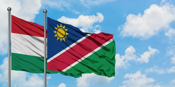 Drapeau de la Hongrie et de la Namibie agitant dans le vent contre ciel bleu nuageux blanc ensemble. Concept de diplomatie, relations internationales . — Photo