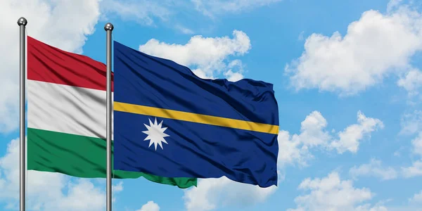 Bandera de Hungría y Nauru ondeando en el viento contra el cielo azul nublado blanco juntos. Concepto diplomático, relaciones internacionales . — Foto de Stock