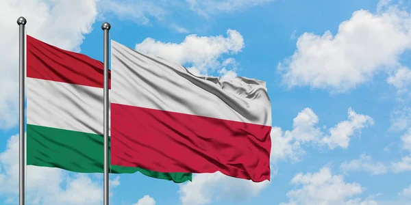 Bandera de Hungría y Polonia ondeando en el viento contra el cielo azul nublado blanco juntos. Concepto diplomático, relaciones internacionales . — Foto de Stock