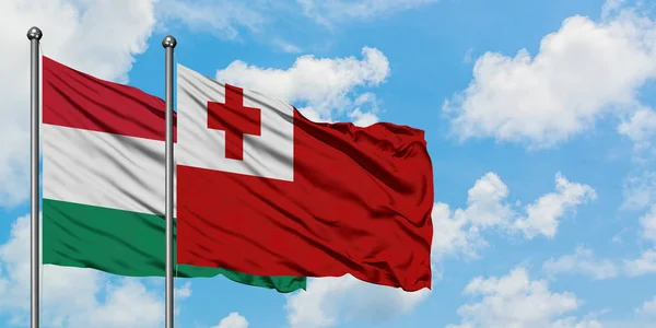 Bandera de Hungría y Tonga ondeando en el viento contra el cielo azul nublado blanco juntos. Concepto diplomático, relaciones internacionales . — Foto de Stock