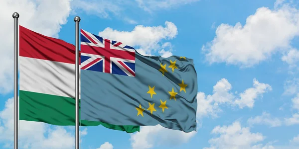 Bandera de Hungría y Tuvalu ondeando en el viento contra el cielo azul nublado blanco juntos. Concepto diplomático, relaciones internacionales . — Foto de Stock