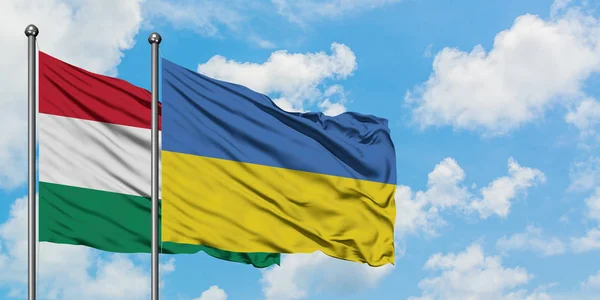 Ungheria e Ucraina bandiera sventolando nel vento contro bianco cielo blu nuvoloso insieme. Concetto di diplomazia, relazioni internazionali . — Foto Stock