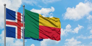 İzlanda ve Benin bayrağı birlikte beyaz bulutlu mavi gökyüzüne karşı rüzgarda sallayarak. Diplomasi kavramı, uluslararası ilişkiler.