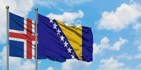 Bandera de Islandia y Bosnia Herzegovina ondeando en el viento contra el cielo azul nublado blanco juntos. Concepto diplomático, relaciones internacionales . — Foto de Stock