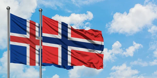 Bandera de Islandia y Bouvet Islands ondeando en el viento contra el cielo azul nublado blanco juntos. Concepto diplomático, relaciones internacionales . — Foto de Stock
