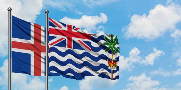 Island och brittiska Indiska oceanen territorium flagga vifta i vinden mot vit grumlig blå himmel tillsammans. Diplomatisk koncept, internationella relationer. — Stockfoto