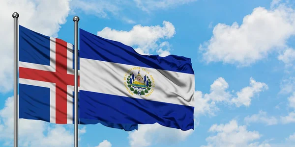 Bandera de Islandia y El Salvador ondeando en el viento contra el cielo azul nublado blanco juntos. Concepto diplomático, relaciones internacionales . — Foto de Stock